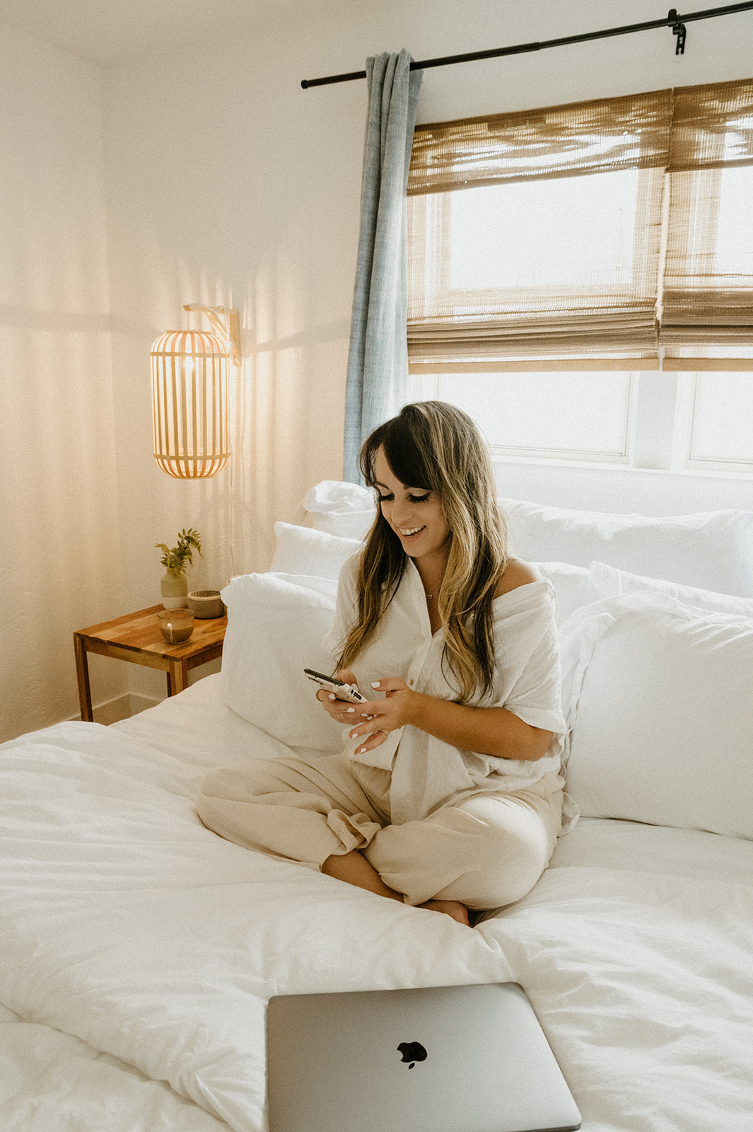 creative business owner using phone app in bright boho room and sharing 8 tools I use as a creative